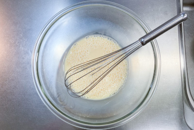 ボウルに卵を割り入れ、牛乳と砂糖を入れ、泡立て器で混ぜ合わせる